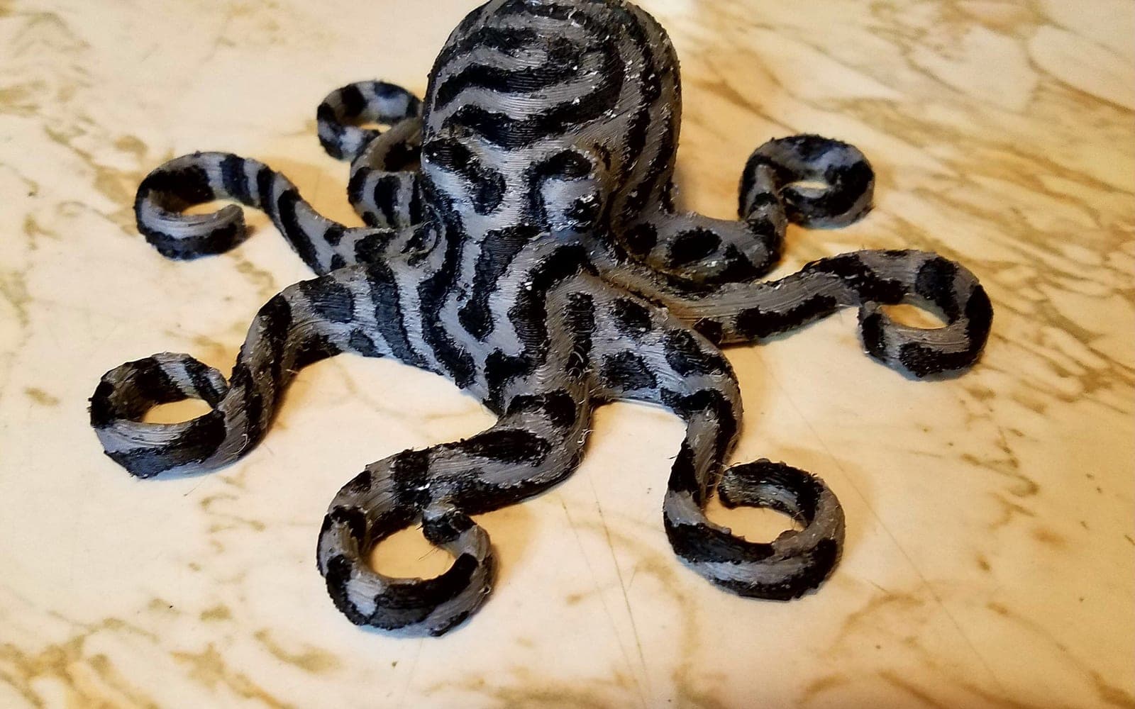 Black 3D printed octopus display model on a tabletop